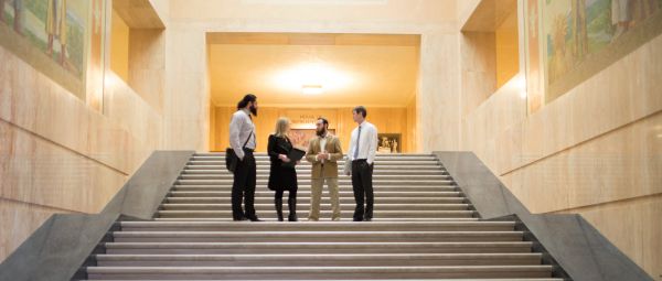 Four people conversing on steps inside Oregon's capitol building