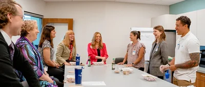 A group of people gathered around a table in an office setting.