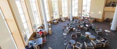 Interior view of a modern academic building's collaborative space, designed to facilitate study and informal gatherings, reflecting an environment conducive to learning and interaction in health management or policy.