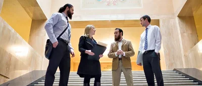 Professionals discussing policy on the steps of a government building, representing advocacy and legislative engagement.