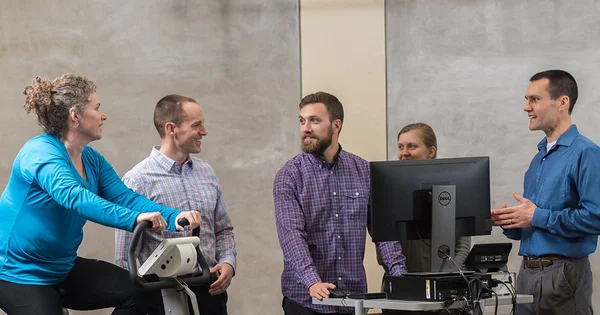 People of different backgrounds gathered around a computer, interacting and sharing ideas.