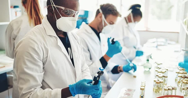 Three people in lab coats and masks working in a laboratory.