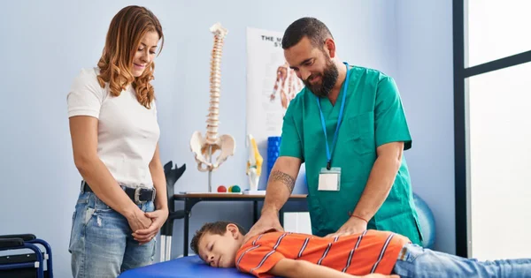 A doctor examining a young patient while a woman stands nearby.