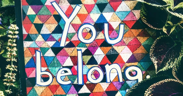 Colorful mosaic background with the words "You belong" in large white letters.
