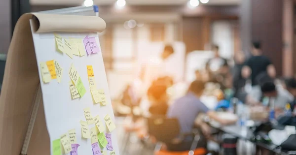 Whiteboard with colorful sticky notes in a blurred office or meeting room setting.