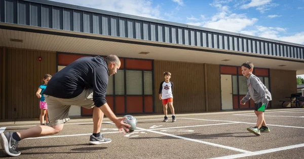 Adult plays four square with three kids