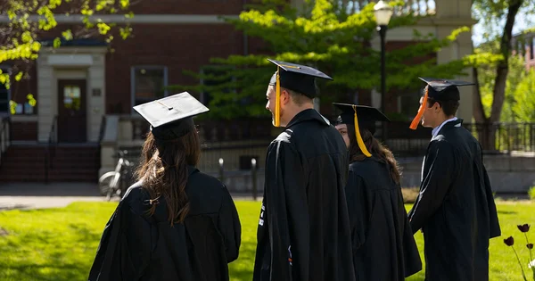 four students walking in their cap and gown