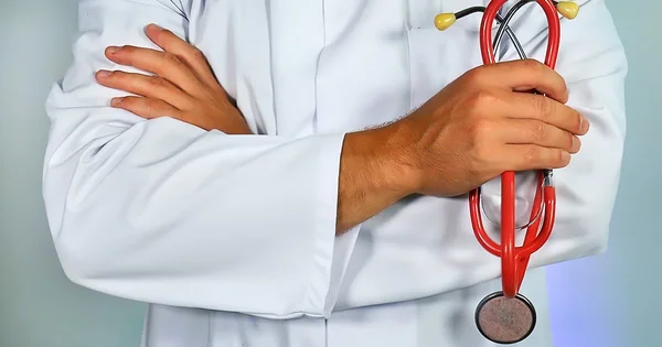 Medical professional in white coat with red stethoscope, arms crossed