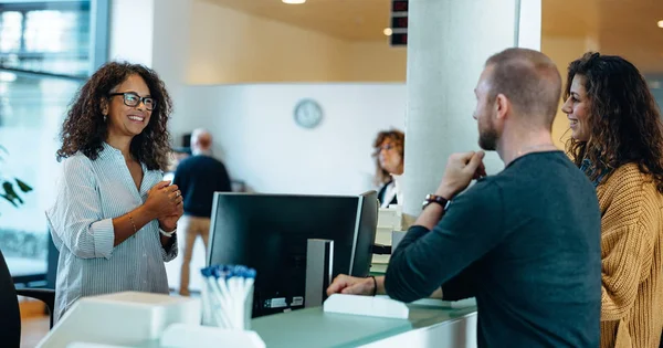 Three people interacting at a service counter in a modern office or clinic.