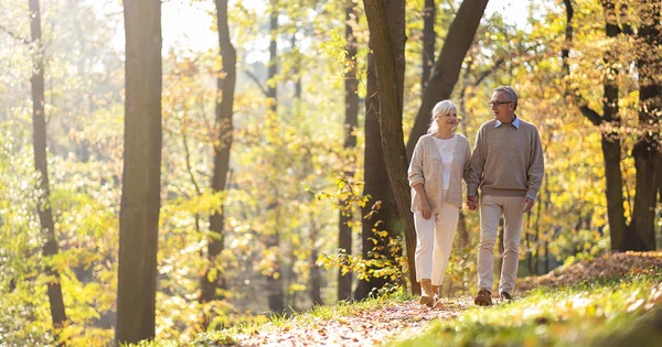 An older man and woman walking together outdoors, symbolizing healthy aging, companionship, and active lifestyles.