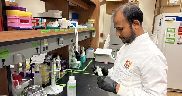 A man wearing a lab coat is engaged in research, examining materials at a laboratory bench.