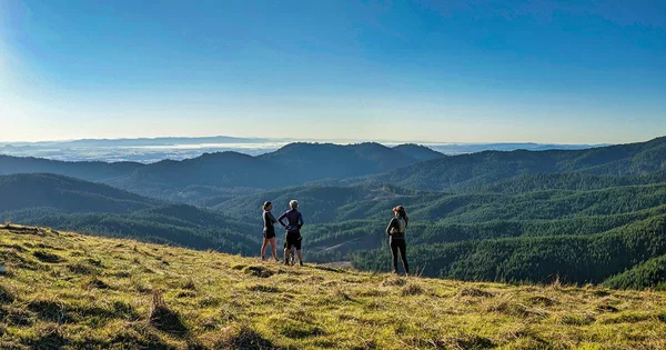 Trail runners pause to enjoy a scenic mountain vista, symbolizing physical activity, exploration, and the appreciation of nature.