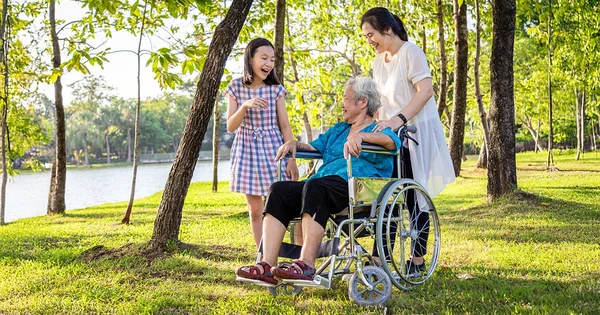 Family members spend time together outdoors, illustrating intergenerational care, companionship, and support in a serene park setting.
