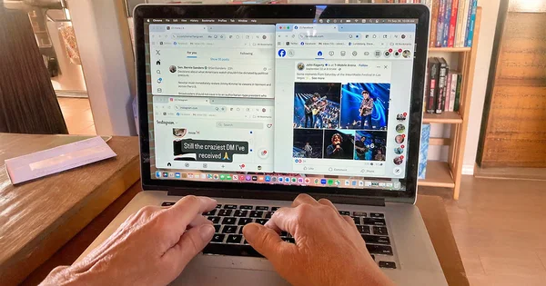 Close-up of a person's hands typing on a laptop displaying multiple browser windows open to news, social media (Facebook, Instagram), and various web tabs.