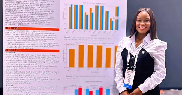 Smiling young female researcher standing in front of her large scientific poster at a conference.