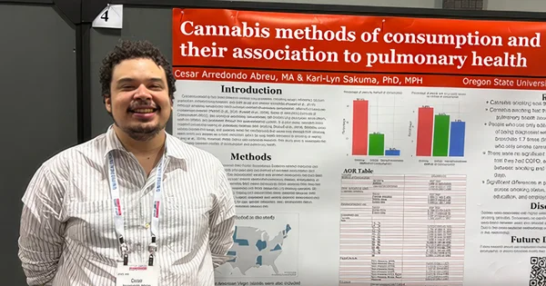 Cesar Arredondo Abreu smiles while standing next to his research poster titled, "Cannabis methods of consumption and their association to pulmonary health."