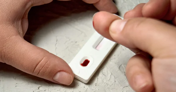 A hand performing a finger-prick blood sample collection for a rapid diagnostic test, symbolizing quick and accessible health screening or disease detection.