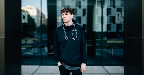 A university student or young professional, possibly in a medical or health field, posing in front of a modern urban building to symbolize career aspiration.