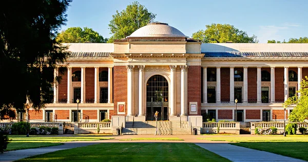 Memorial Union building on OSU Corvallis campus. A person stands on the steps, possibly entering or exiting the building. A green lawn leads to the entrance.