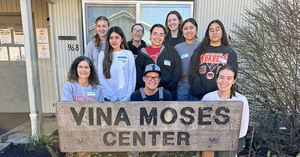 HDFS Club volunteers at the Vina Moses Center, smiling and posing in front of the center's sign.