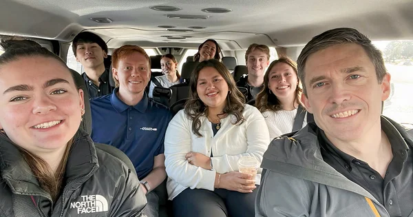 Smiling colleagues traveling together in a shuttle van, capturing a shared group moment during a trip.
