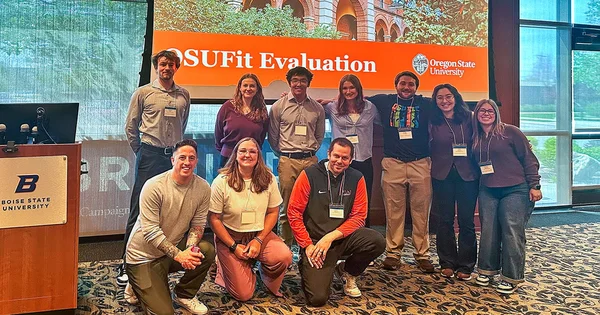 Nine participants pose in front of a presentation screen displaying OSUFit Evaluation and the Oregon State University logo.