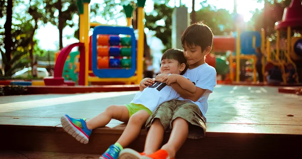 Two happy children embracing on a playground, symbolizing community, friendship, and positive social interaction.
