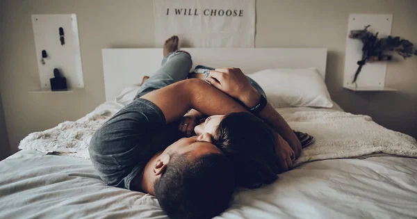 A couple embracing in bed, symbolizing intimacy, connection, and consent, which is relevant to a sexual and relationship health context.