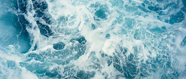 Close-up view of turbulent ocean waves with frothy white sea foam.