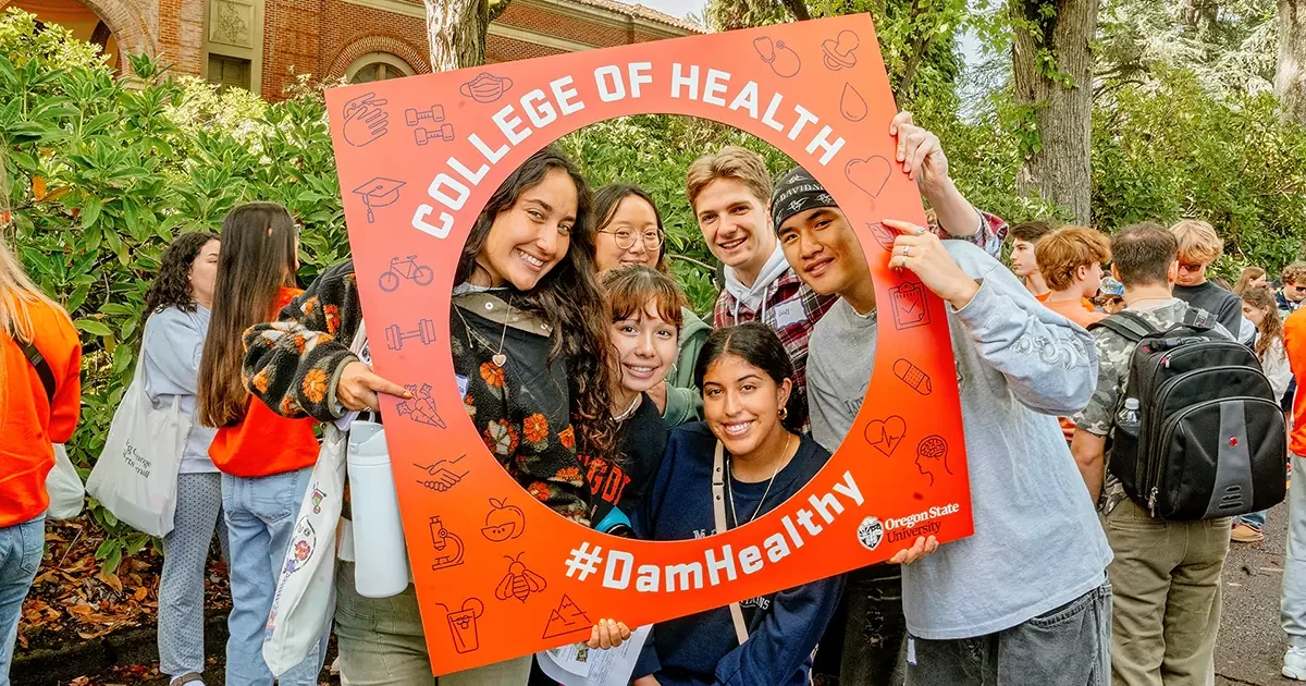A group of students holding a large orange banner that says "College of Health" and "#DamHealthy".