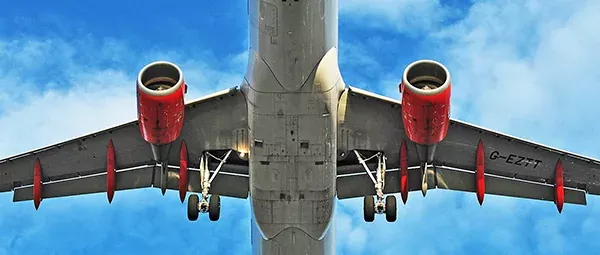 Underside of a large airplane, showing engines, landing gear, and wingspan.