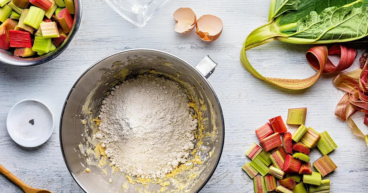 A bowl of chopped rhubarb and a mixing bowl with a batter-like mixture.
