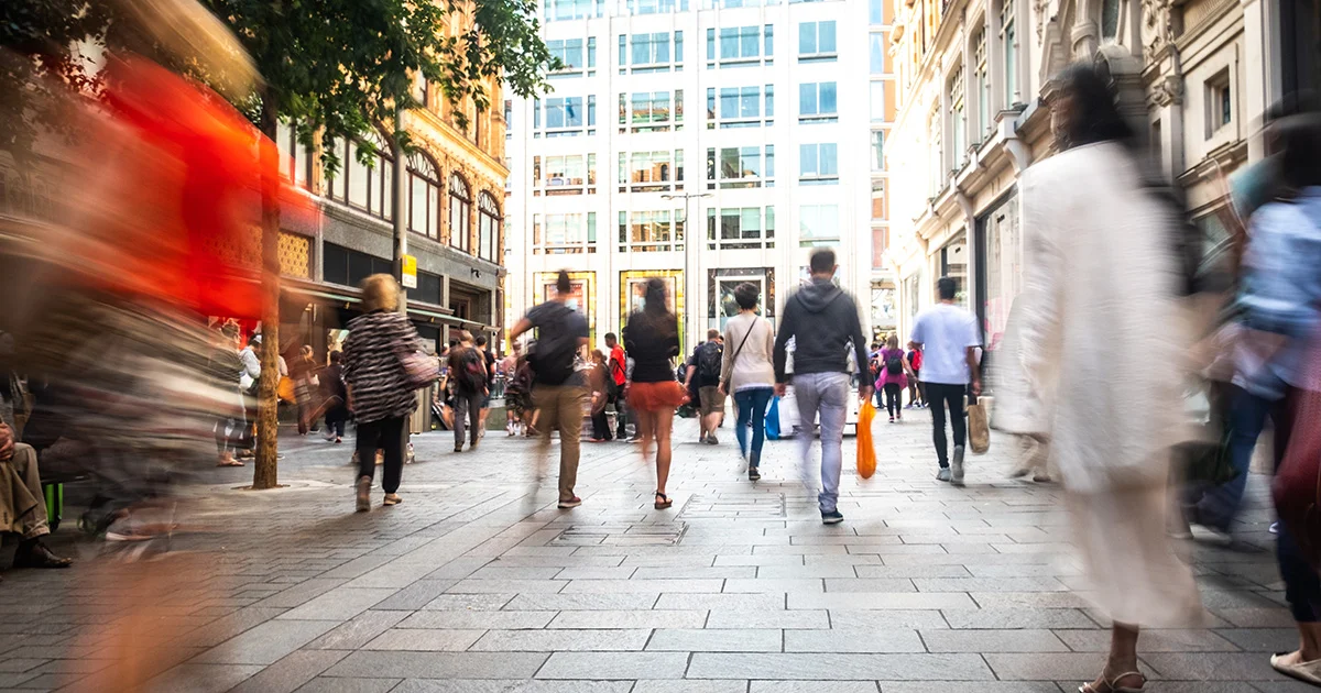  Crowded city street with people walking and buildings in the background.