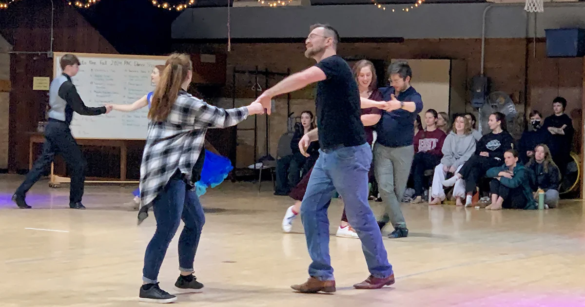 People dancing in a room with an audience.