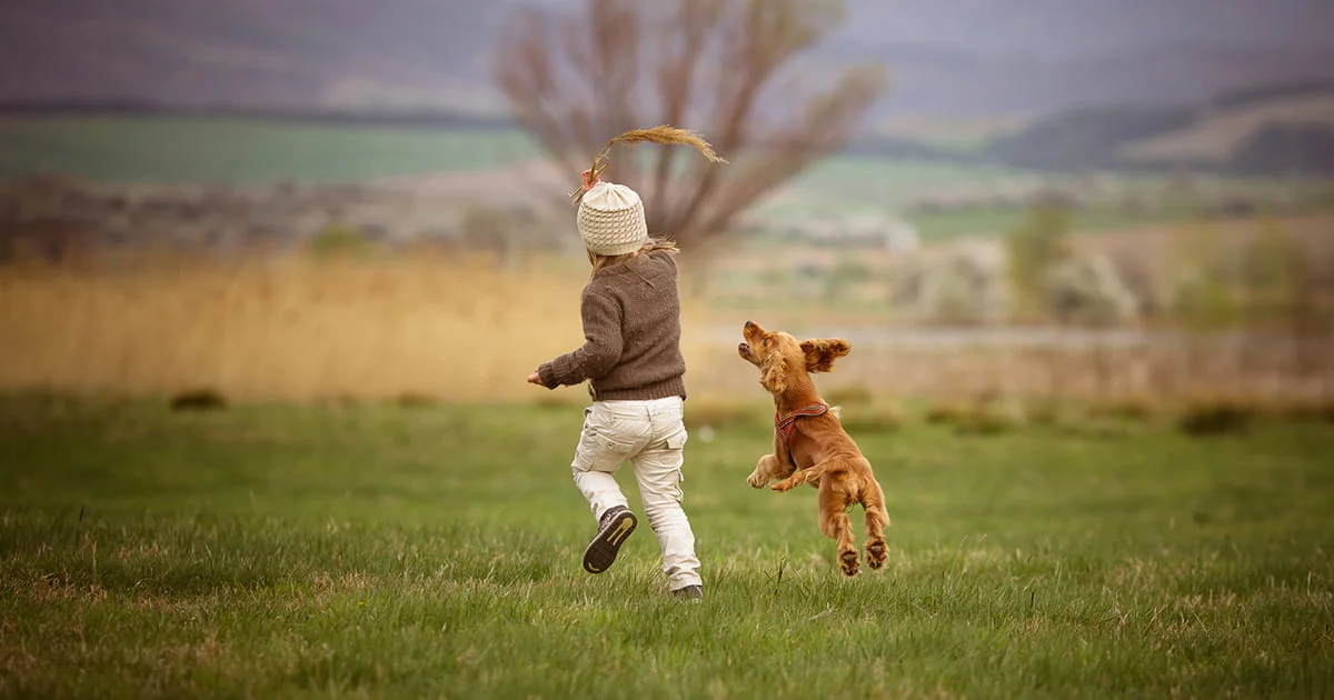 child playing outside with dog