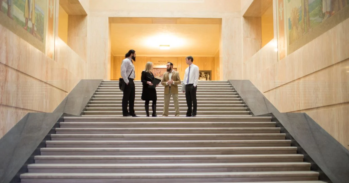 Four people conversing on steps inside Oregon's capitol building