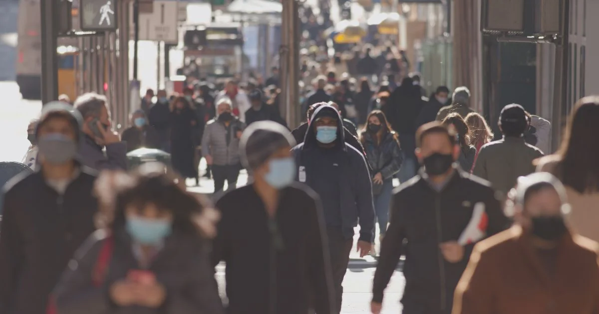 People wearing masks walking on a city sidewalk