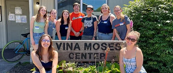A group of people posing in front of a sign that reads 'Vina Moses Center'. They are smiling and appear to be enjoying a sunny day.