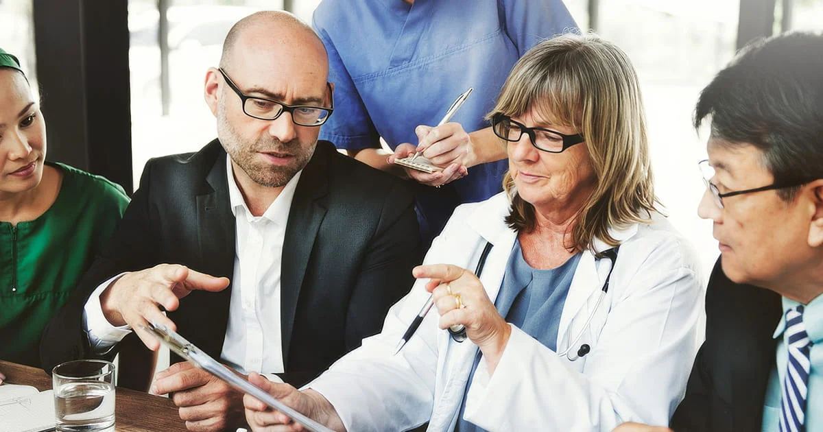 Medical and public health professionals collaborating in a meeting, examining data or a patient chart, symbolizing teamwork in healthcare.
