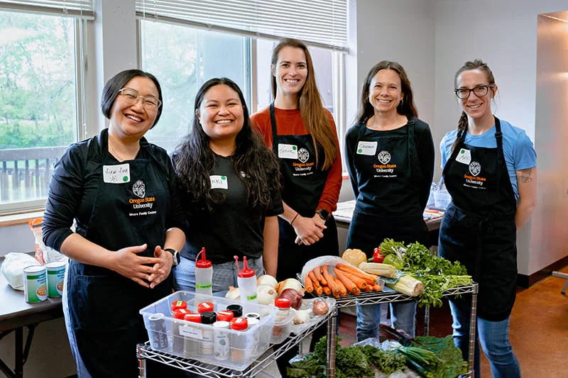 Students and staff at the Oregon State University College of Health pose during a hands-on nutrition or cooking class, demonstrating practical learning.