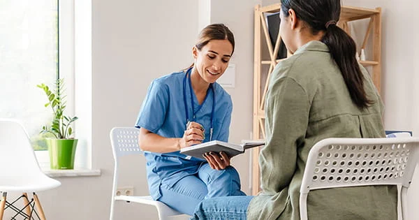 A doctor or medical assistant consults with a patient, illustrating the patient care and communication involved in a pre-med or pre-health profession.