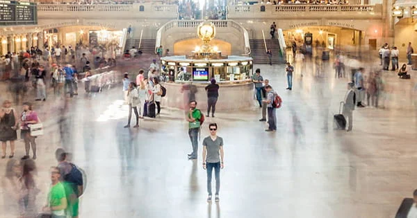 A person standing alone in a crowd, illustrating the concepts of individuality, urban public spaces, and the impact of health on large populations.