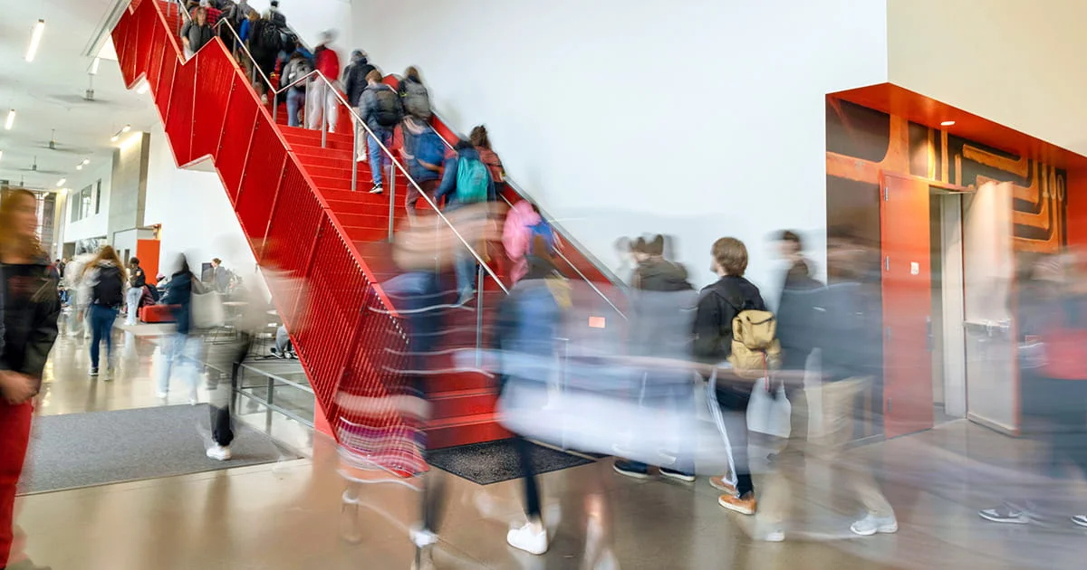 Students moving between classes in a university building, highlighting the dynamic and active environment for studying kinesiology.