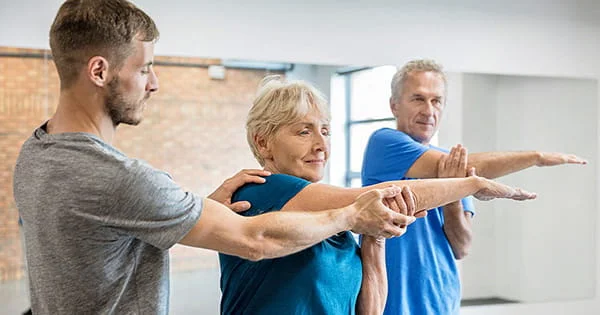 A young professional works with older adults, illustrating the practical application of kinesiology.