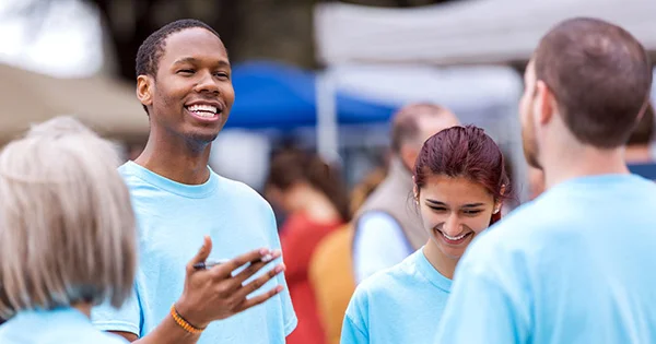 People in uniform shirts collaborating at a community event, representing public health outreach and teamwork.