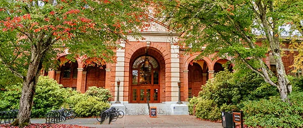 A large, historic campus building with an arched entrance, representing the academic community.