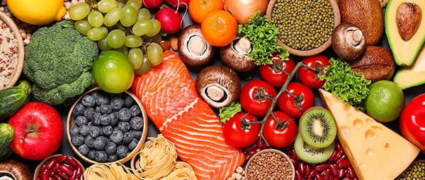 A colorful arrangement of healthy foods, including fish, cheese, fruits, vegetables, and grains.