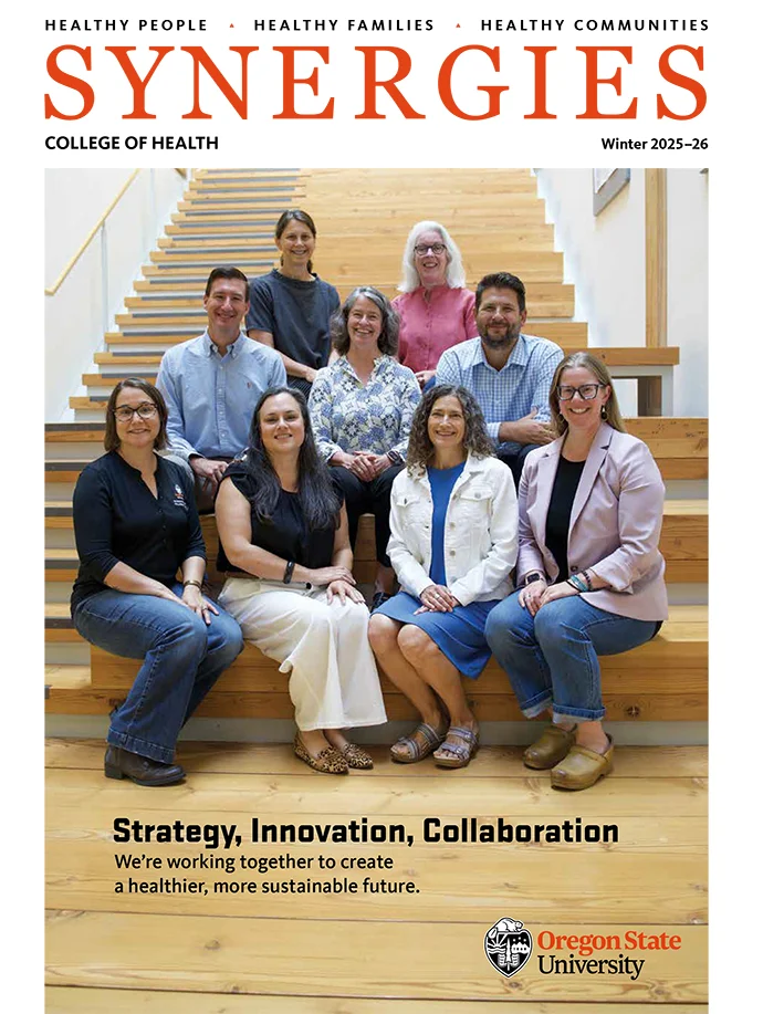 Cover of SYNERGIES magazine, Winter 2025-26, featuring nine smiling College of Health faculty and staff members posing on a wooden staircase.