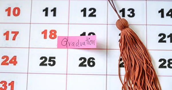 Visual representation of the academic calendar, highlighting a date marked for Graduation with a sticky note and a graduation tassel.