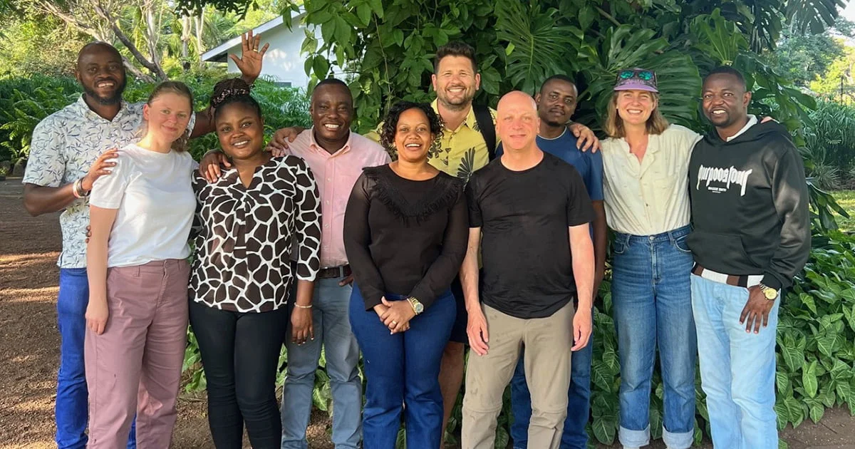 A diverse team of researchers and staff from different backgrounds smiling together, representing a successful international collaboration.